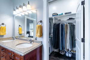 Bathroom featuring double vanity, wood finished floors, and a spacious closet