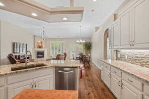 Kitchen featuring a chandelier, stainless steel dishwasher, dark wood-style flooring, decorative backsplash, and recessed lighting