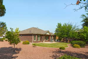 Rear view of property featuring brick siding, a patio, and a lawn