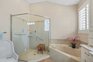 Full bath featuring plenty of natural light, a tub with jets, a stall shower, and tile patterned floors