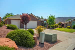 Ranch-style house with brick siding, an attached garage, driveway, and a mountain view