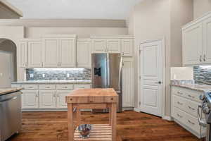 Kitchen with appliances with stainless steel finishes, decorative backsplash, and white cabinets