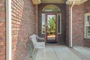 View of exterior entry featuring brick siding and covered porch