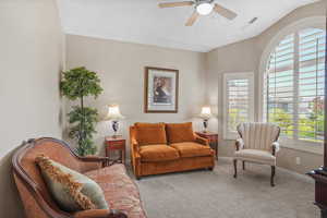 Carpeted living area featuring plenty of natural light, a ceiling fan, and lofted ceiling