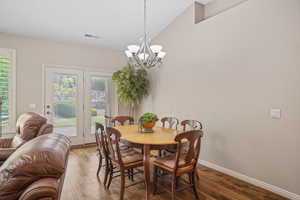 Dining room with a chandelier, vaulted ceiling, and wood finished floors