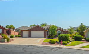 Ranch-style home with a garage, driveway, a tile roof, and brick siding