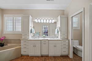 Full bath with double vanity, a garden tub, and tile patterned floors