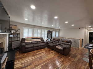 Living area with wood-type flooring, recessed lighting, a textured ceiling, and a fireplace