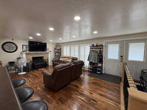Living room with hardwood / wood-style flooring, a textured ceiling, a fireplace, and recessed lighting