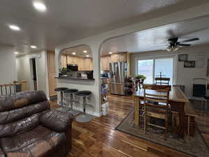 Dining area featuring arched walkways, dark wood-style floors, ceiling fan, recessed lighting, and a textured ceiling