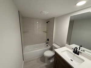 Full bath with vanity, wood finished floors, tub / shower combination, and a textured ceiling