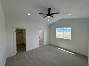 Unfurnished bedroom with a spacious closet, carpet floors, lofted ceiling, recessed lighting, and a ceiling fan