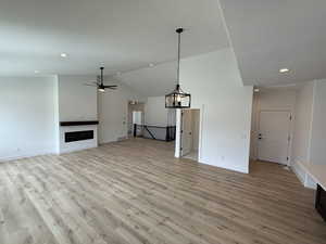 Unfurnished living room with light wood-style floors, lofted ceiling, recessed lighting, ceiling fan, and a fireplace