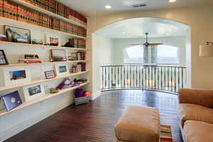 Living area with wood finished floors, arched walkways, ceiling fan, and recessed lighting