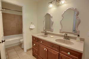 Bathroom featuring tile patterned flooring, double vanity, and shower / washtub combination