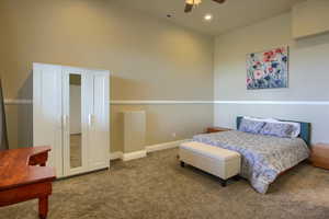 Carpeted bedroom with ceiling fan, recessed lighting, and a high ceiling