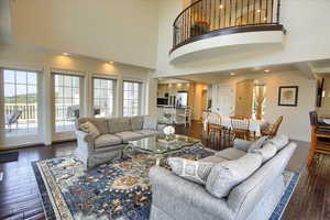 Living room with healthy amount of natural light, arched walkways, hardwood / wood-style flooring, and a high ceiling