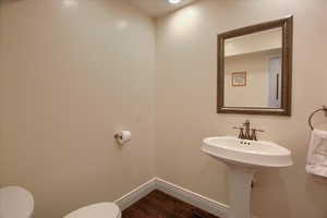 Half bathroom featuring toilet and wood finished floors