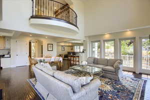 Living room with arched walkways, dark wood-style floors, and a high ceiling