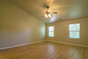 Unfurnished room featuring wood finished floors, ceiling fan, and lofted ceiling