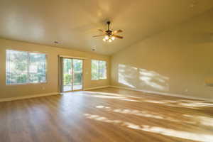 Spare room featuring light wood-style floors, ceiling fan, and vaulted ceiling