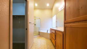 Full bathroom with a shower stall, a garden tub, double vanity, and a spacious closet