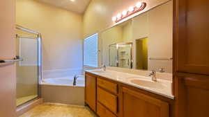 Full bath featuring double vanity, a garden tub, and a shower stall