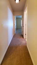 Hallway featuring light carpet and baseboards