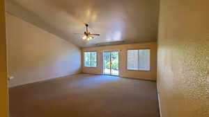 Carpeted spare room featuring ceiling fan and vaulted ceiling