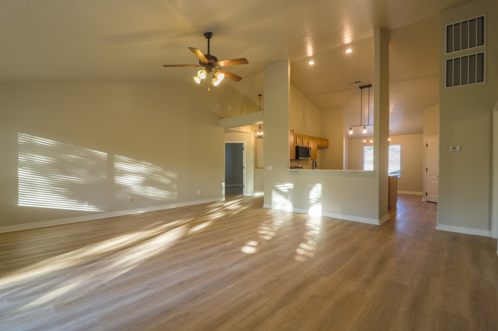 Unfurnished living room featuring light wood-style floors, ceiling fan, and vaulted ceiling