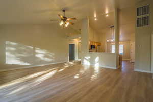 Unfurnished living room featuring light wood-style floors, ceiling fan, and vaulted ceiling