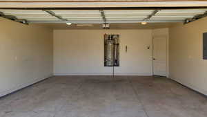 Garage featuring water heater, electric panel, and a garage door opener