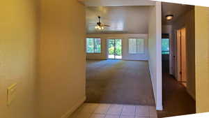 Hall featuring light carpet, light tile patterned floors, and lofted ceiling