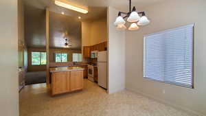 Kitchen featuring white appliances, high vaulted ceiling, a chandelier, decorative light fixtures, and light floors