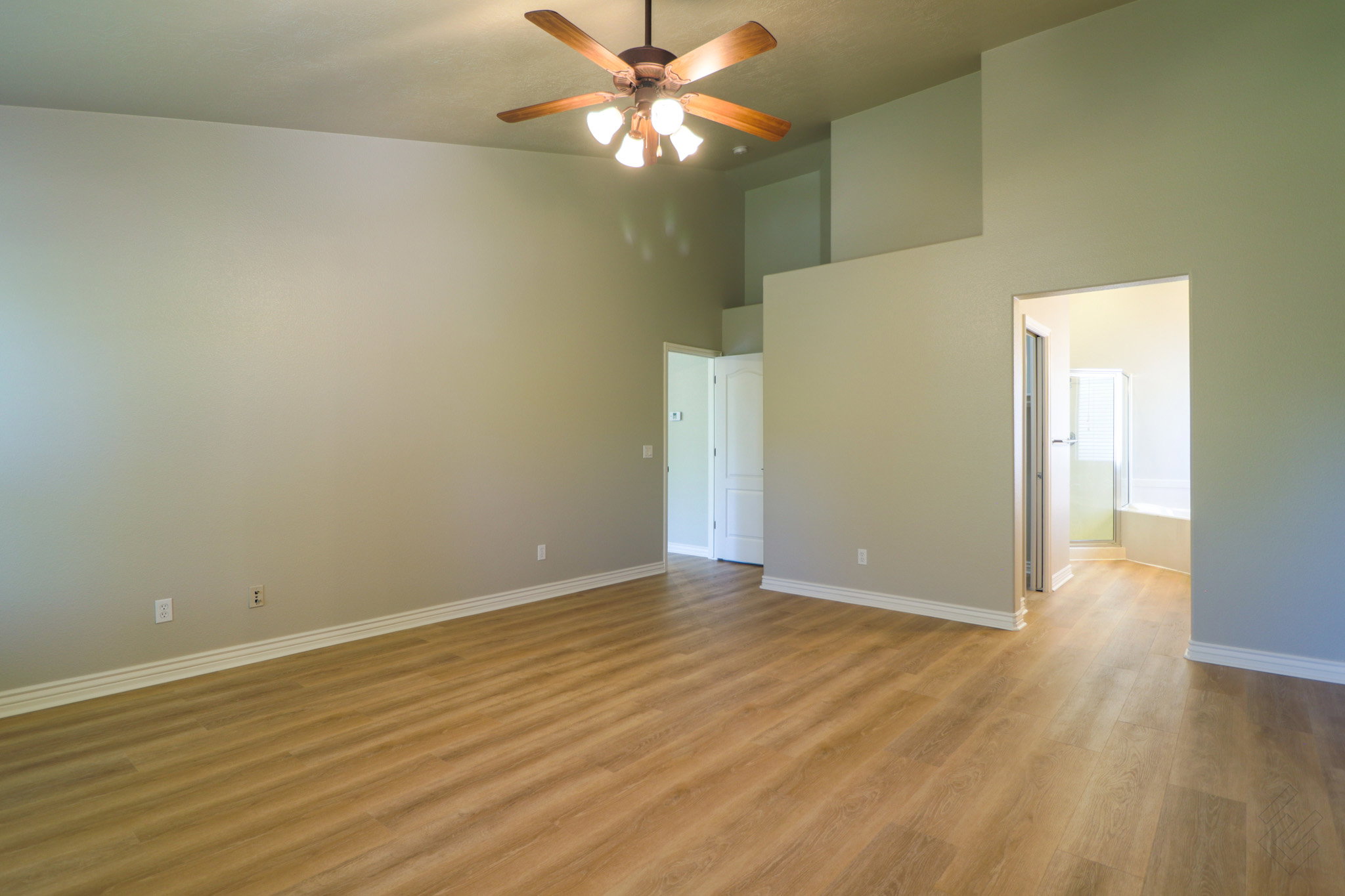 Spare room with light wood-type flooring, a high ceiling, and ceiling fan