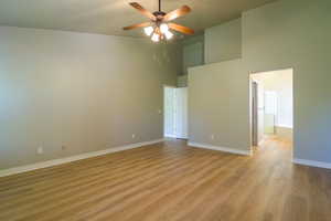 Spare room with light wood-type flooring, a high ceiling, and ceiling fan