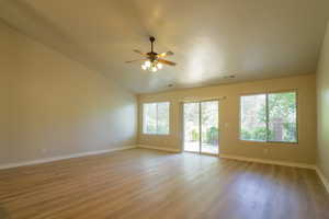 Empty room with light wood finished floors, ceiling fan, and vaulted ceiling