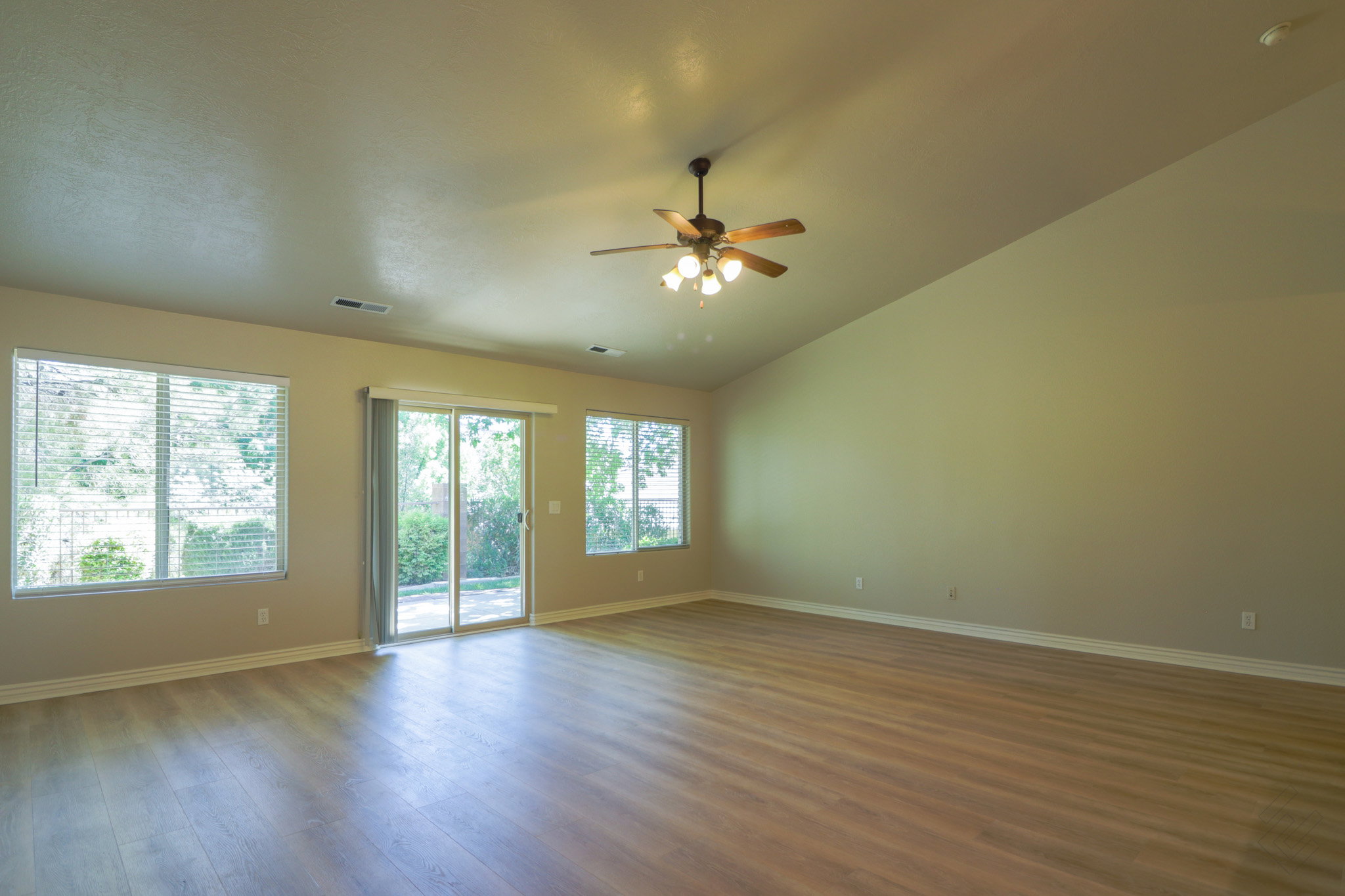 Empty room with dark wood-type flooring, a ceiling fan, and lofted ceiling