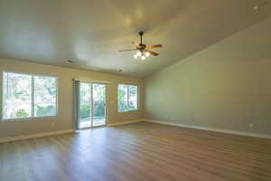 Empty room with dark wood-type flooring, a ceiling fan, and lofted ceiling