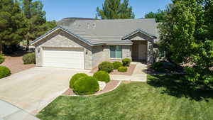 Ranch-style house with a garage, concrete driveway, a tiled roof, brick siding, and a front yard