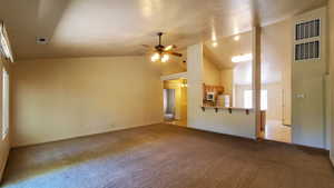 Unfurnished living room with healthy amount of natural light, ceiling fan, lofted ceiling, and carpet floors