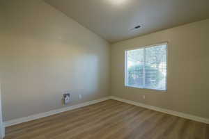 Empty room with vaulted ceiling and wood finished floors