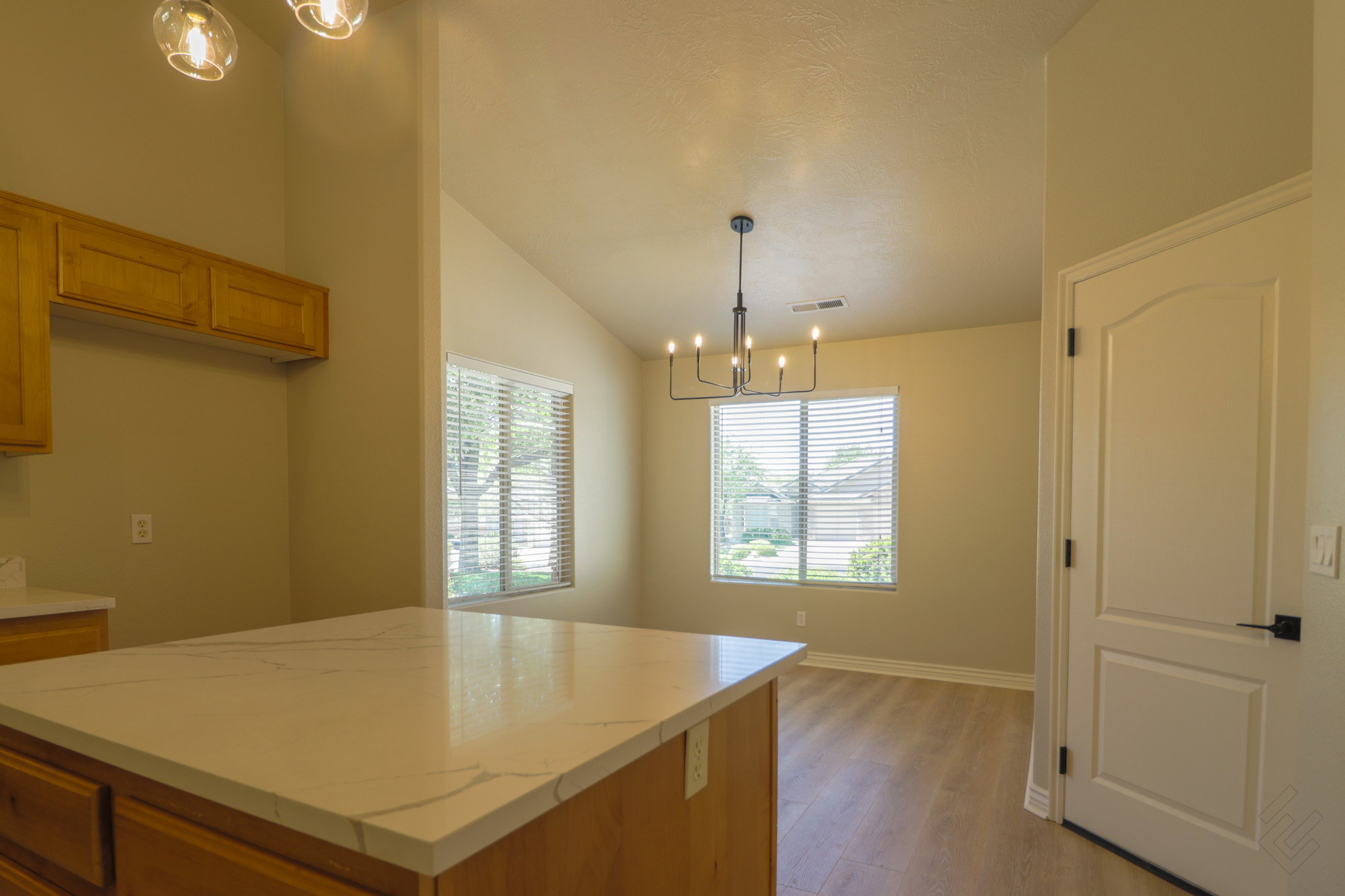 Kitchen with a center island, lofted ceiling, light wood-style flooring, a chandelier, and wood finish cabinetry