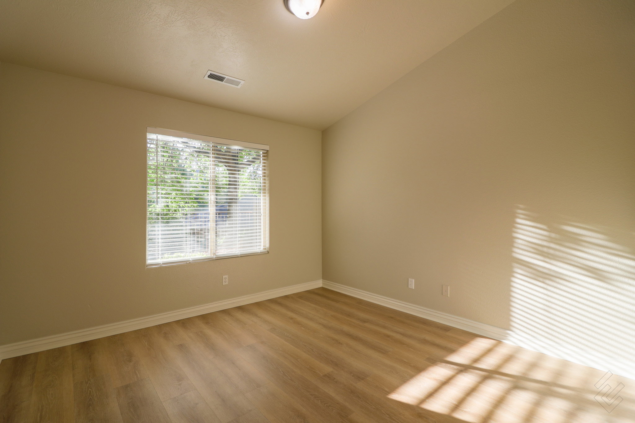 Empty room with vaulted ceiling and light wood finished floors