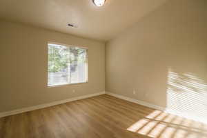 Empty room with vaulted ceiling and light wood finished floors