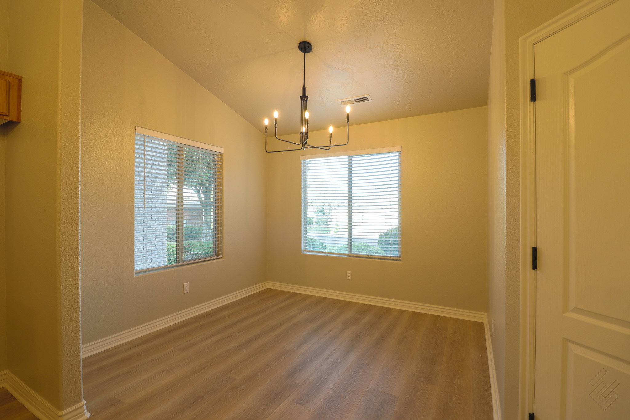 Unfurnished room featuring dark wood-type flooring, hanging lights, and vaulted ceiling
