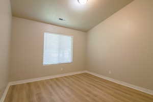 Unfurnished room with vaulted ceiling and light wood-style floors