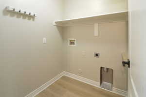 Laundry area with light wood finished floors, washer hookup, and hookup for an electric dryer