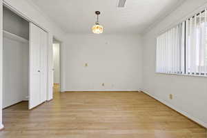 Unfurnished bedroom with light wood-style flooring, ornamental molding, and a closet