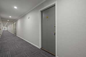 Hallway featuring dark carpet, recessed lighting, and ornamental molding
